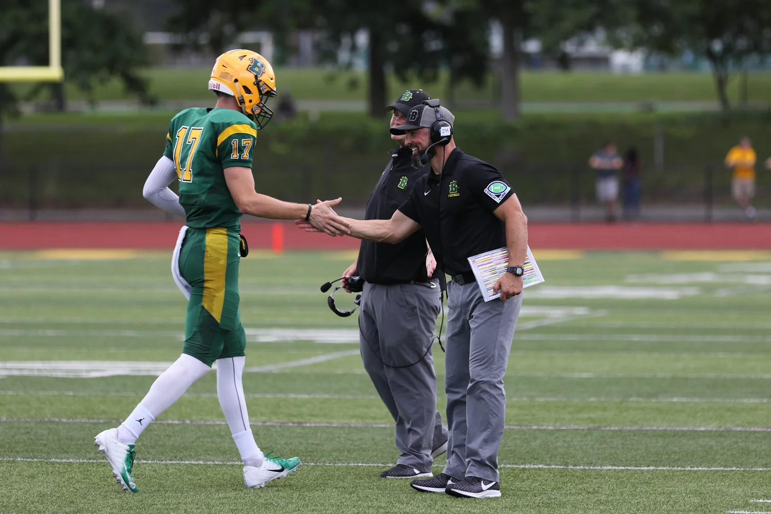 Coach Mangone slapping the hand of the player coming off the field