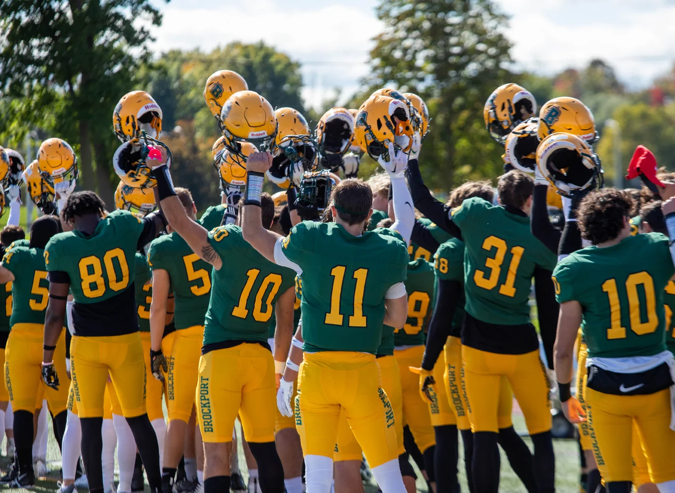 Brockport raises their helmets during the National Anthem
