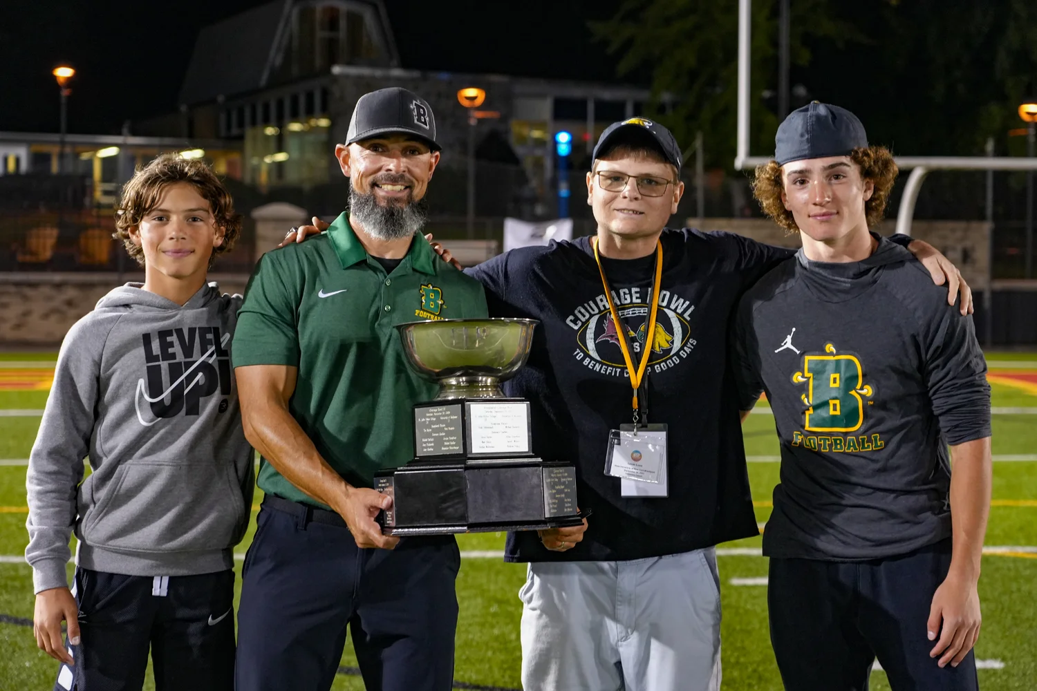 Coach posing with the boys holding the trophy